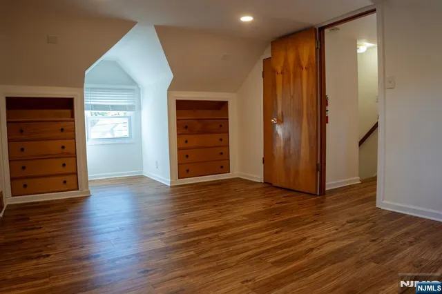 an empty room with wooden floor closet and windows