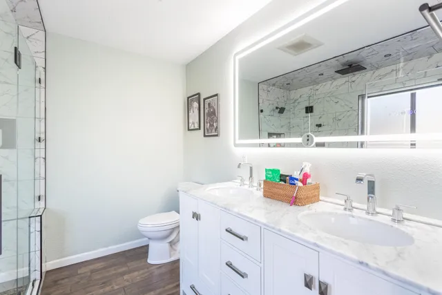 a bathroom with a granite countertop sink mirror vanity and toilet