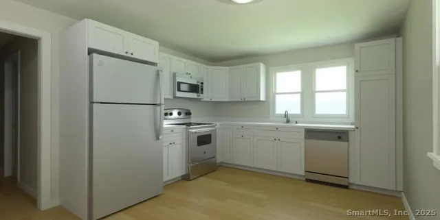 a kitchen with cabinets appliances a sink and a window