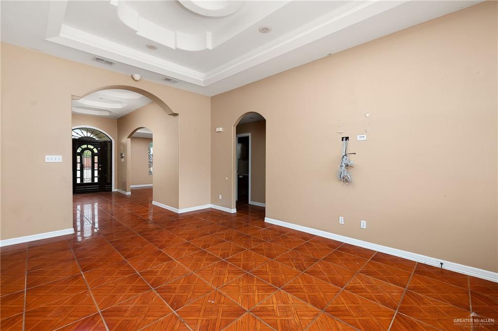 1315 Ruger Street Donna, TX 78537 - Photo 4 of 17 The living area features intricate tile flooring, arched doorways, and a tray ceiling with crown molding, enhancing the sophisticated design