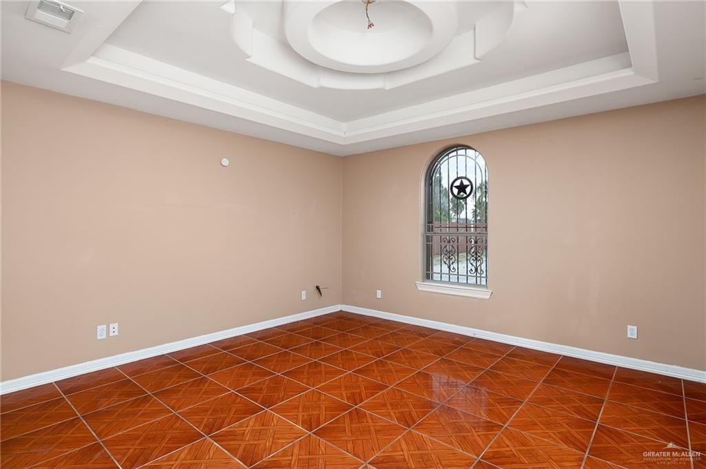 1315 Ruger Street Donna, TX 78537 - Photo 8 of 17 This room features a decorative tray ceiling, an arched window with an ornate iron grill, and patterned tile flooring