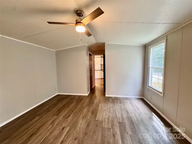 an empty room with wooden floor fan and windows