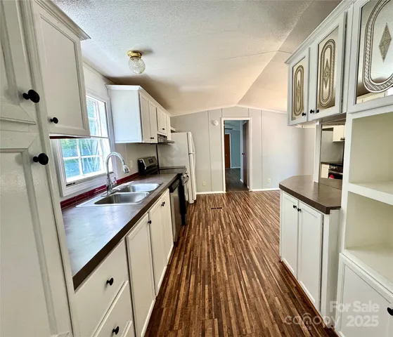 a kitchen with granite countertop a sink stove refrigerator and cabinets
