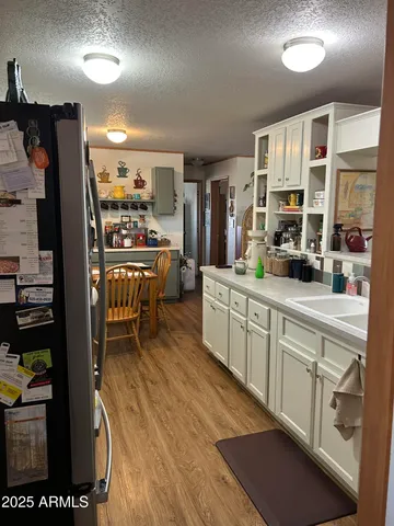 a kitchen with stainless steel appliances granite countertop a refrigerator a stove a sink dishwasher and white cabinets with wooden floor