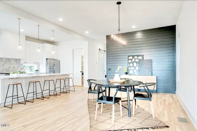 a view of a dining room and livingroom with furniture wooden floor a rug a chandelier and a view