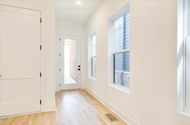 a view of an empty room with wooden floor and a window