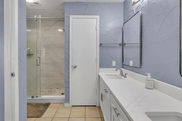 a bathroom with a double vanity sink mirror and shower