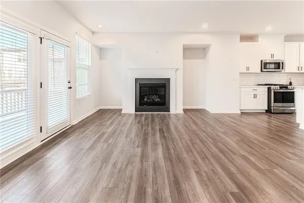 an empty room with wooden floor a fireplace and windows