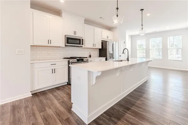 a large kitchen with stainless steel appliances granite countertop a stove a sink dishwasher and a refrigerator with wooden floor