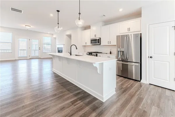 a kitchen with stainless steel appliances a refrigerator sink a stove a microwave and a hard wood floors