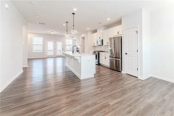 a large kitchen with a wooden floor and stainless steel appliances