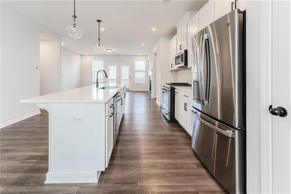 a kitchen with kitchen island a counter top space a sink a refrigerator and a stove
