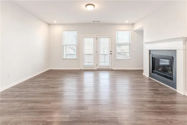 an empty room with wooden floor fireplace and windows