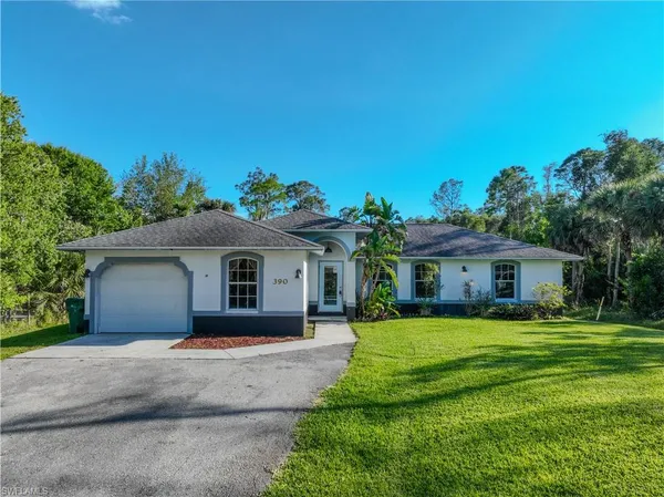 a front view of a house with a garden and trees