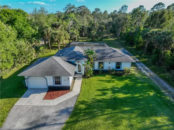 a aerial view of a house next to a big yard and large trees
