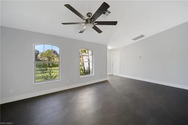 an empty room with windows and ceiling fan