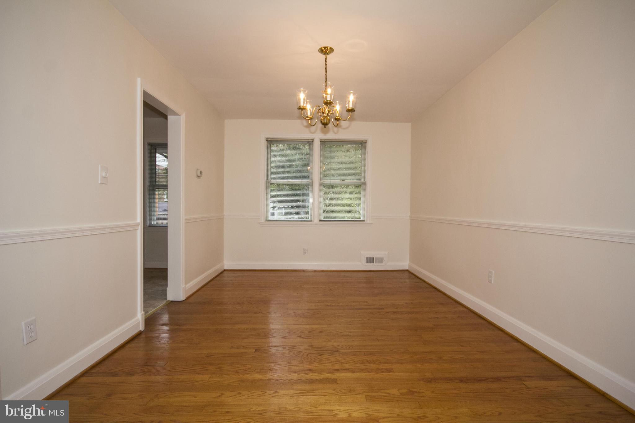 5626 Sagra Road Baltimore, MD 21239 - Photo 6 of 27 an empty room with chandelier fan and windows
