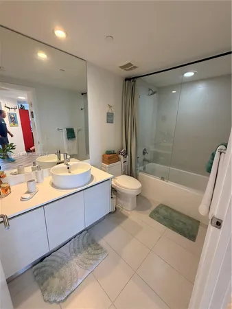 a bathroom with a double vanity sink a toilet and shower