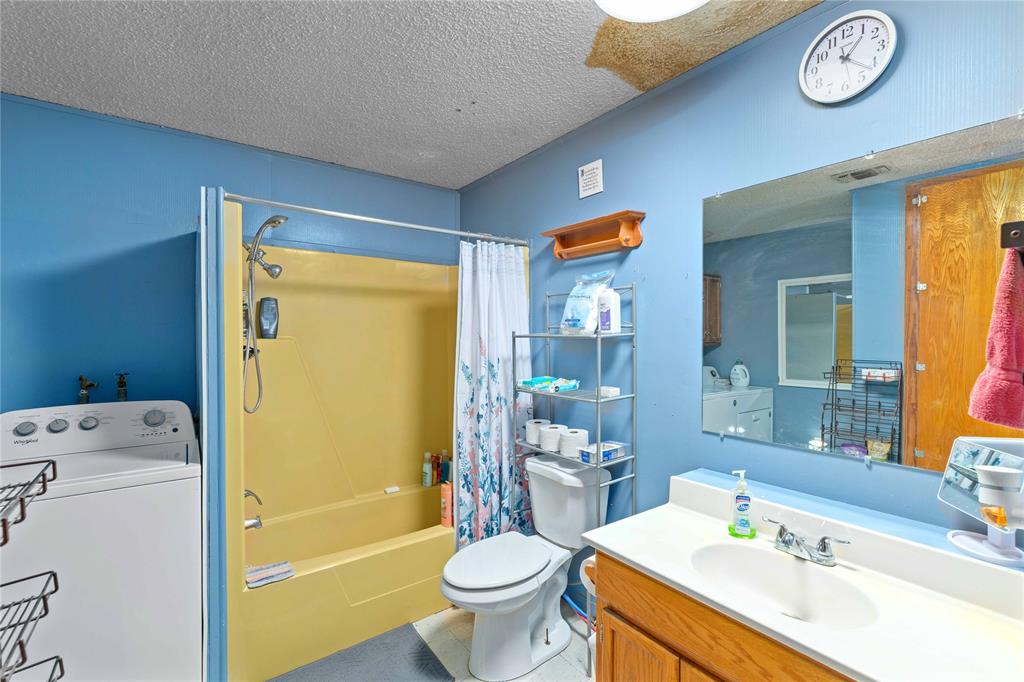 309 Goodwin Street Bangs, TX 76823 - Photo 14 of 20 Full bathroom with washer / clothes dryer, shower / bath combo, vanity, and a textured ceiling