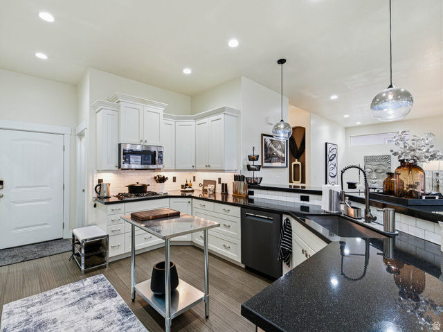 1154 Sunset Dunes Way Draper, UT 84020 - Photo 16 of 50 Kitchen with white cabinets, decorative light fixtures, dark stone counters, and tasteful backsplash