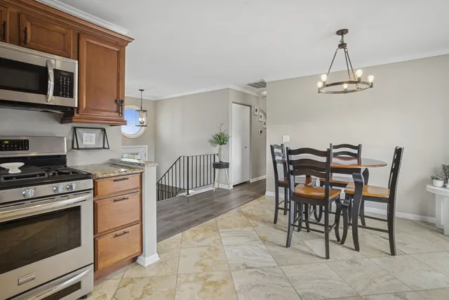 a kitchen with stainless steel appliances granite countertop a stove a microwave a dining table and chairs with wooden floor