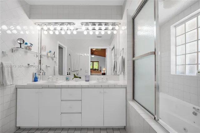 a bathroom with a double vanity sink mirror and bathtub