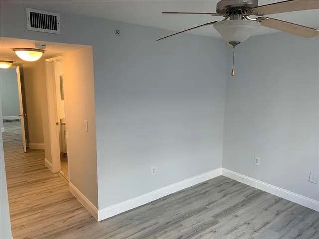 a view of a room with wooden floor and a ceiling fan