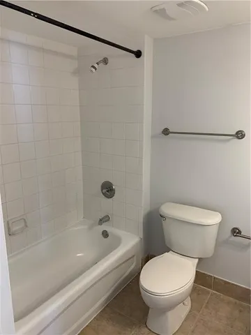 a white toilet sitting next to a bath tub and a shower