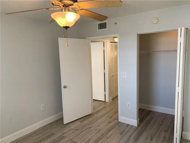 a view of a room with wooden floor and a ceiling fan