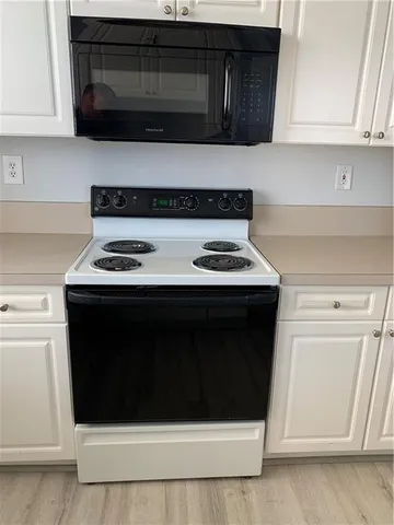 a kitchen with stainless steel appliances a stove a microwave and a white cabinets