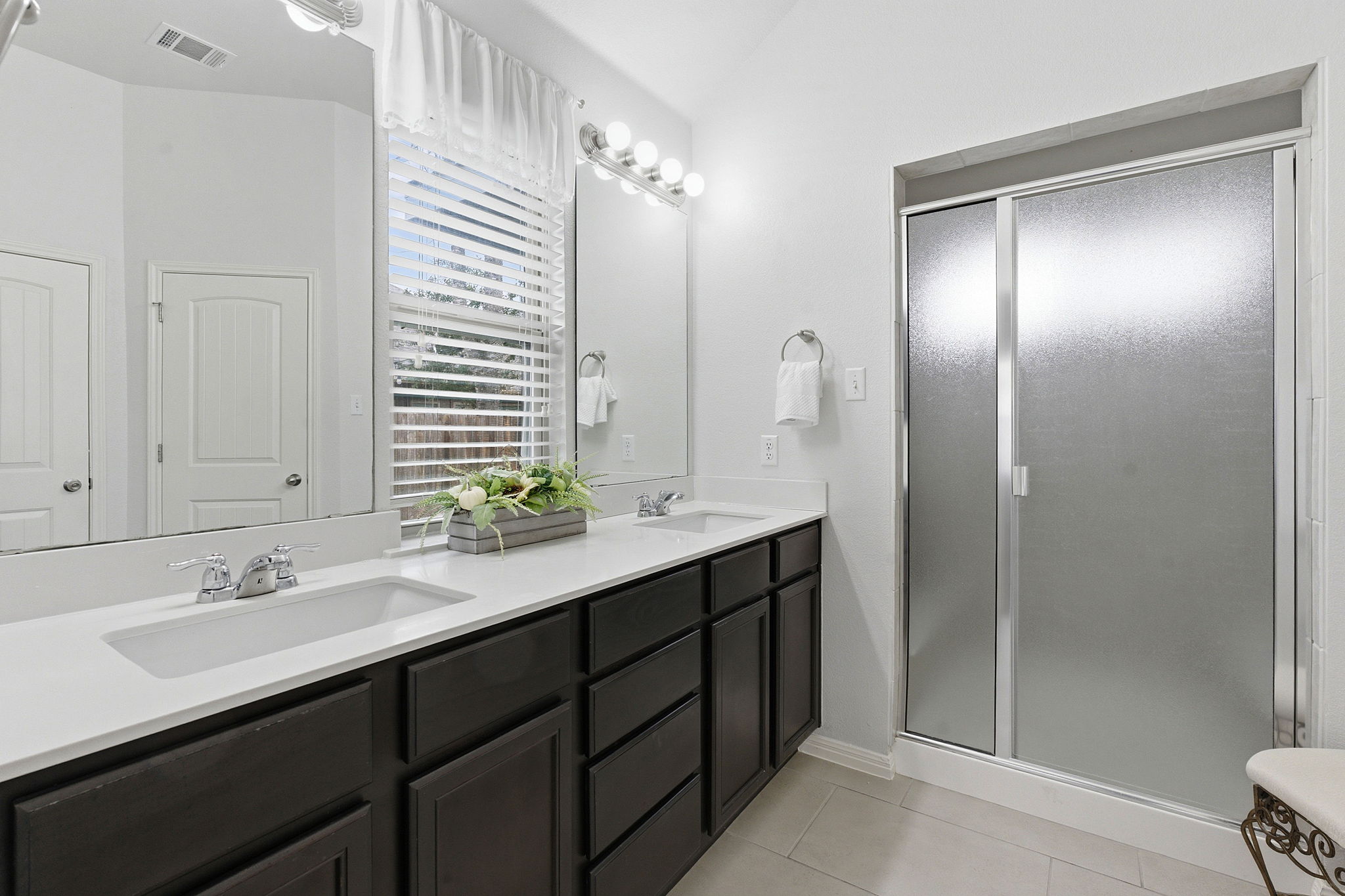 426 Tilly Lane Buda, TX 78610 - Photo 11 of 21 Bathroom with double vanity, a shower stall, light tile patterned floors, and vaulted ceiling