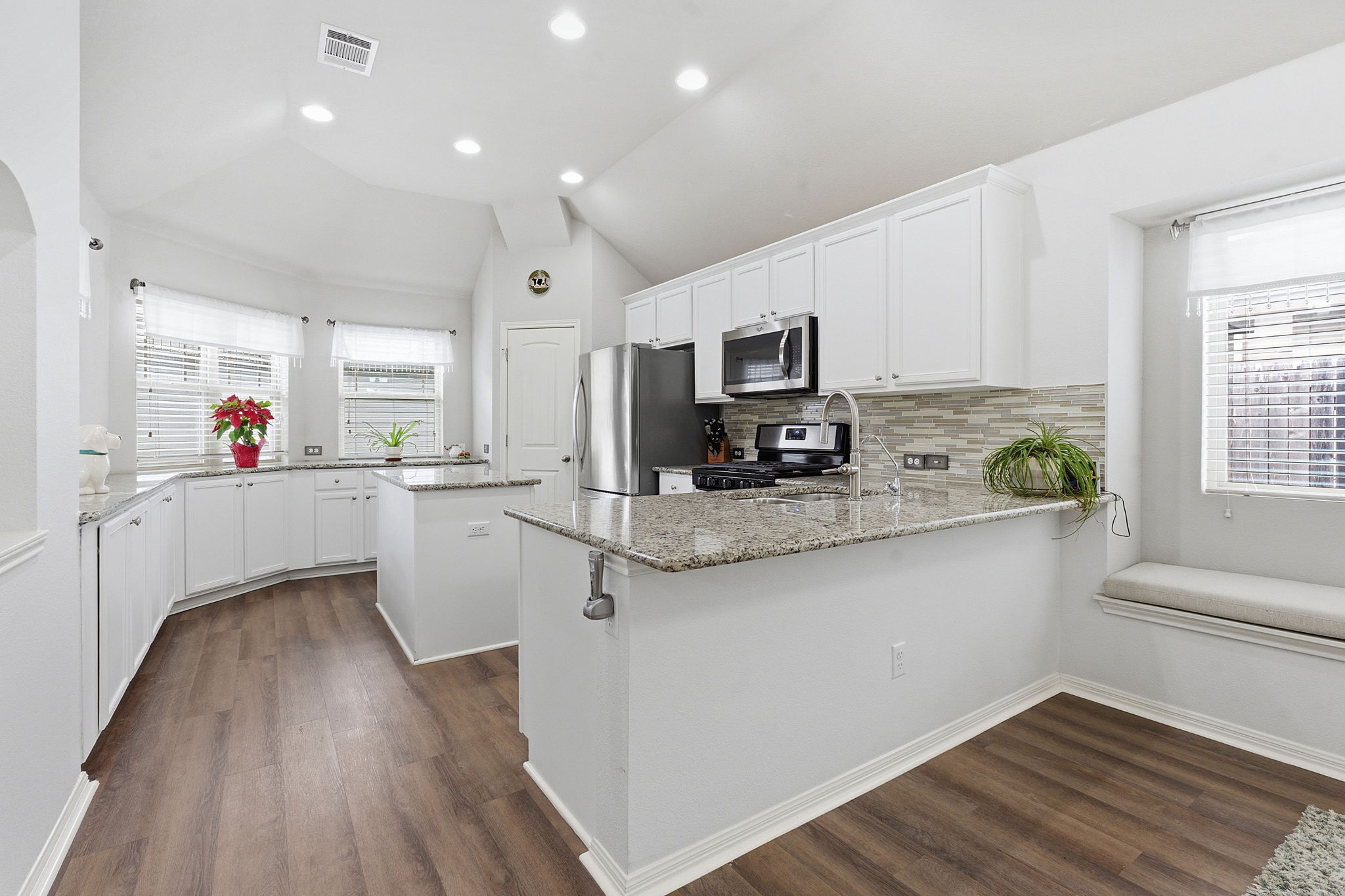426 Tilly Lane Buda, TX 78610 - Photo 6 of 21 Kitchen featuring a center island, white cabinets, backsplash, a peninsula, and lofted ceiling