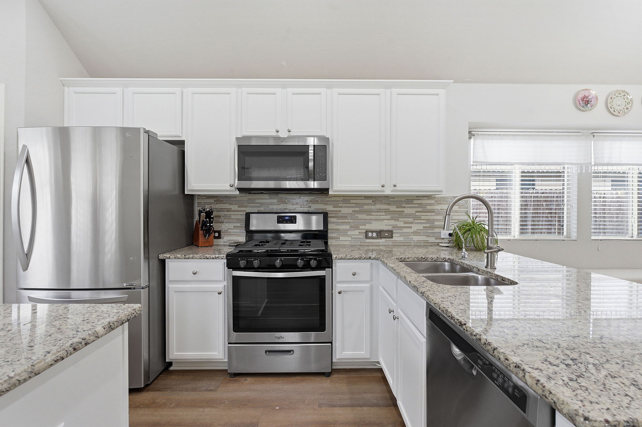 426 Tilly Lane Buda, TX 78610 - Photo 8 of 21 Kitchen featuring stainless steel appliances, white cabinets, light stone counters, and light wood finished floors