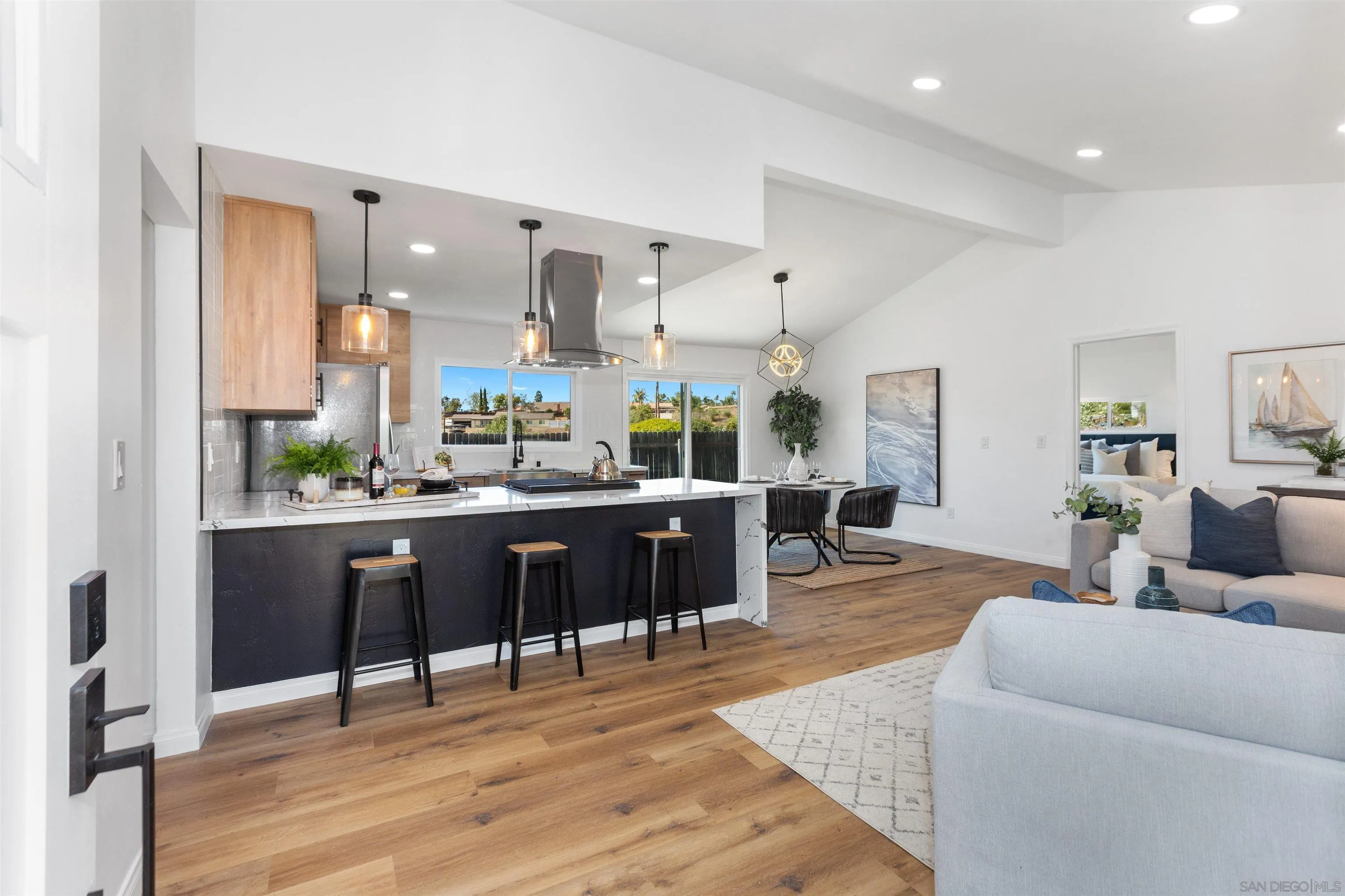 12694 Jackson Heights Drive El Cajon, CA 92021 - Photo 3 of 29 a living room with stainless steel appliances kitchen island granite countertop furniture and a wooden floor