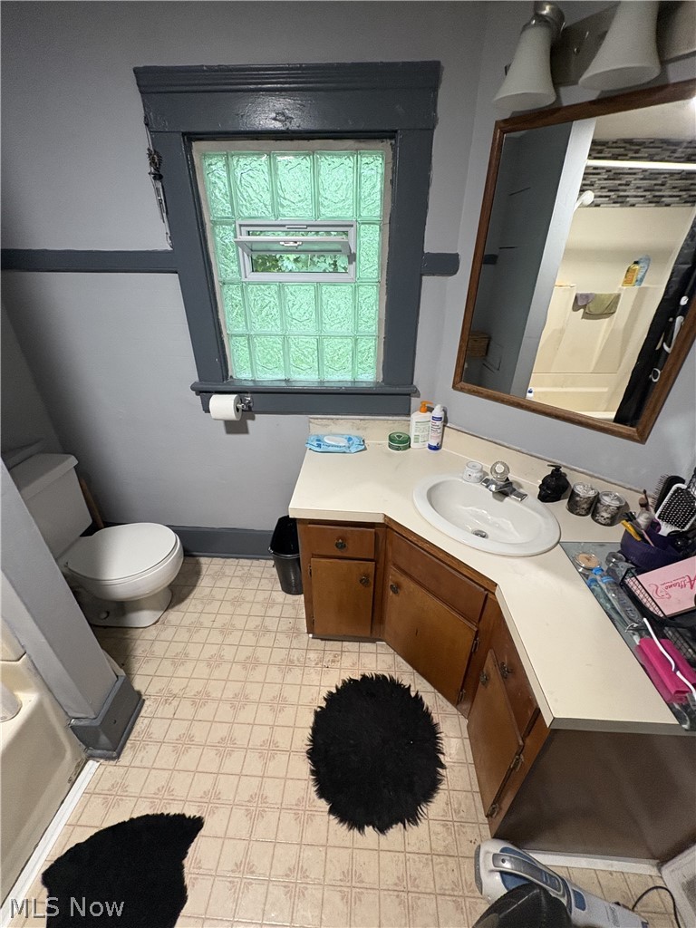 727 Wooster Road North Barberton, OH 44203 - Photo 28 of 37 729 (1-Bed) - Bathroom featuring a corner vanity with an integrated sink, a glass block window with an operable vent, and a wall-mounted light fixture above a framed mirror