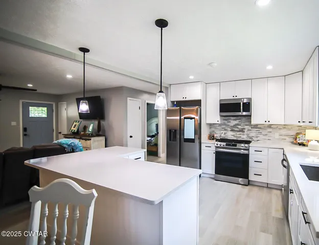 a large kitchen with cabinets stainless steel appliances and a chandelier