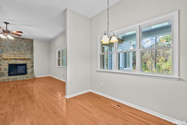 a view of an empty room with a window and chandelier fan