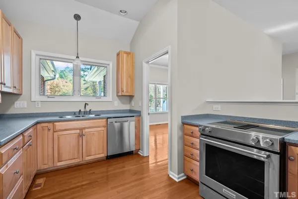 a kitchen with stainless steel appliances granite countertop a stove a sink and a wooden floors