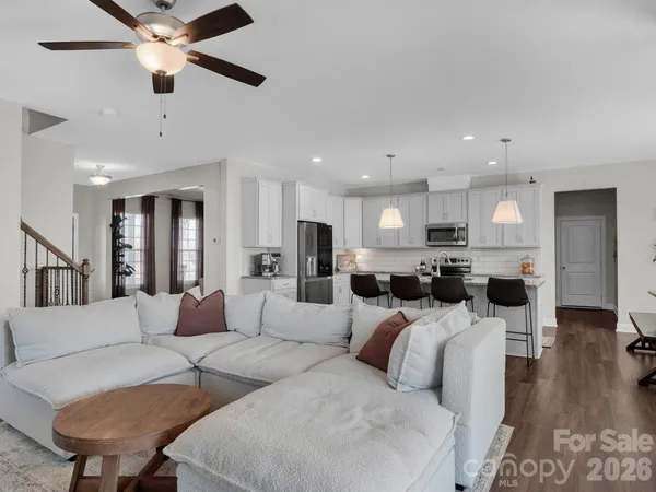 a living room with couches kitchen view and a chandelier