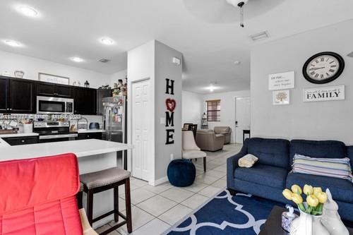 3772 Southeast 2nd Drive, Unit 3772 Homestead, FL 33033 - Photo 5 of 36 a living room with furniture a clock and a view of kitchen