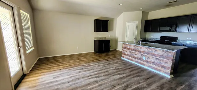 a kitchen with stainless steel appliances granite countertop a stove and a wooden floor