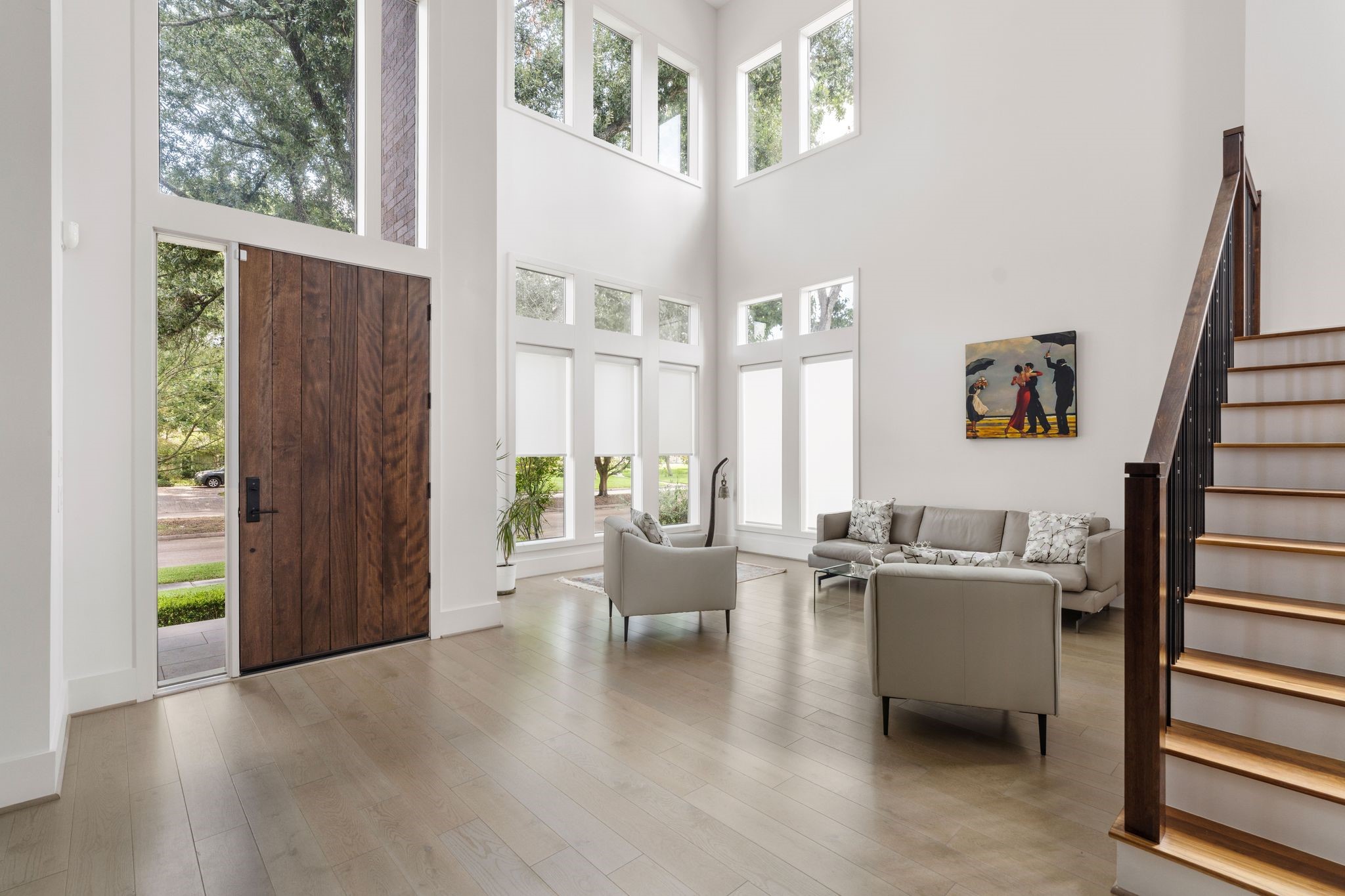 5427 Maple Street Houston, TX 77096 - Photo 8 of 46 Looking back toward the entry, the front door stands open to the street, framed by tall transom windows above and a clean run of stairs rising along the right wall.