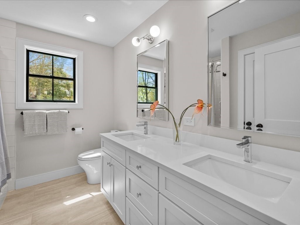 90 Norfolk Street Needham, MA 02492 - Photo 30 of 42 a bathroom with a double vanity sink a toilet and a mirror