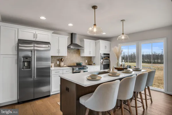 a kitchen with a refrigerator a stove a sink a dining table and chairs