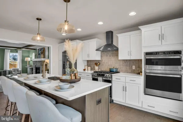 a kitchen with stainless steel appliances kitchen island granite countertop a stove a sink a dining table and chairs with wooden floor