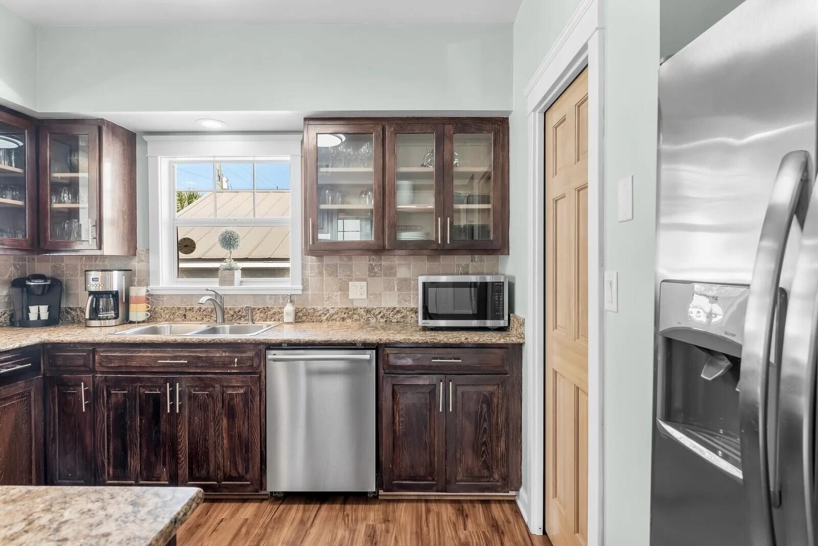 4503 John Avenue Destin, FL 32541 - Photo 12 of 51 a kitchen with stainless steel appliances granite countertop a stove a sink and a refrigerator with wooden cabinets