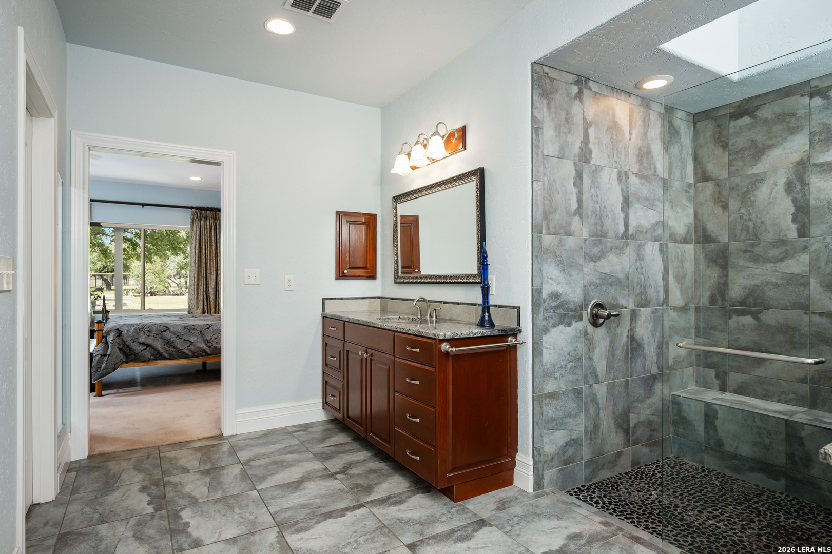 613 Saxet Trail Spring Branch, TX 78070 - Photo 25 of 50 a bathroom with a granite countertop sink a mirror and shower