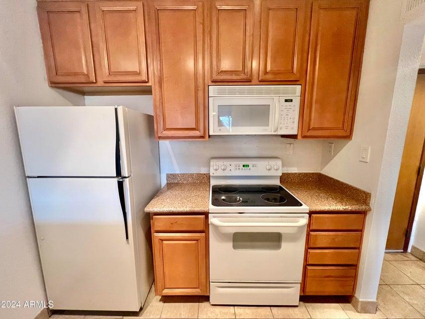 7625 East Camelback Road, Unit 415A Scottsdale, AZ 85251 - Photo 9 of 17 a kitchen with appliances a refrigerator and cabinets