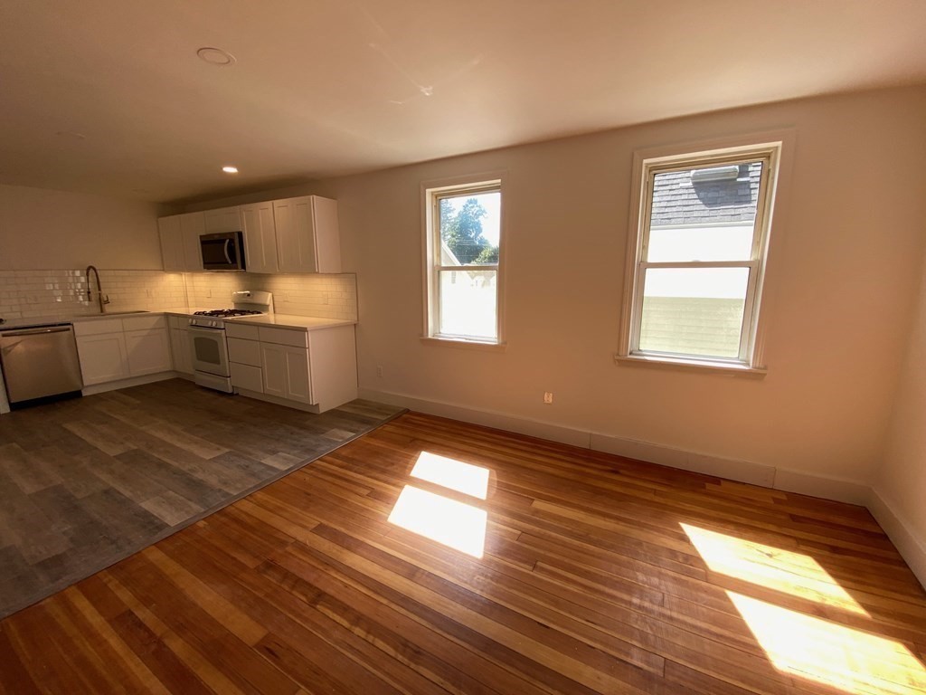 23 Main Street, Unit 2 Topsfield, MA 01983 - Photo 7 of 16 a large white kitchen with wooden floor and a sink