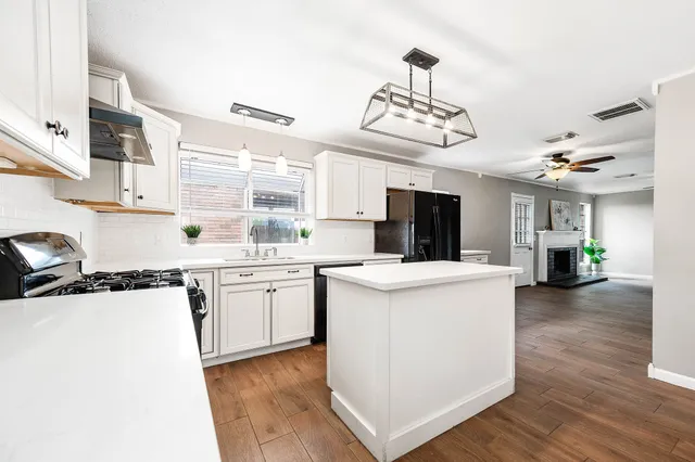 a kitchen with kitchen island a sink counter top space appliances and cabinets